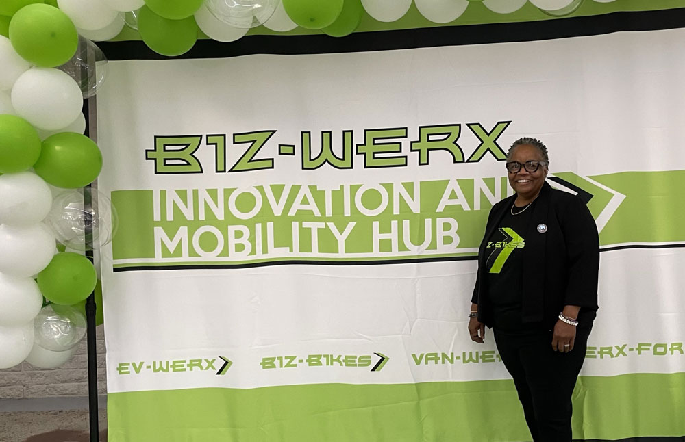 Casandra Little stands in front of a Biz-Werx Innovation and Mobility Hub sign