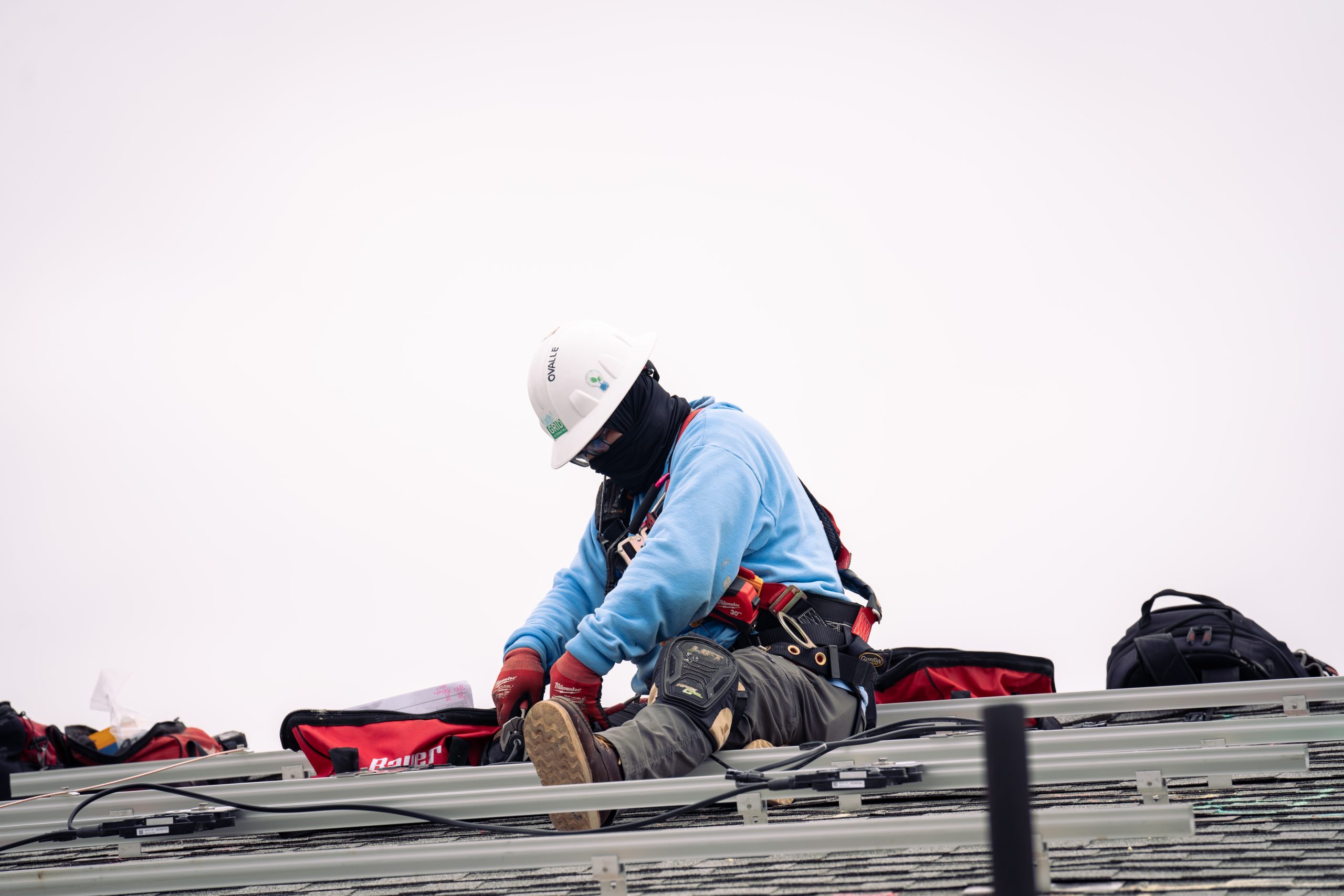 man sitting on a roof wearing a hard hat and harness