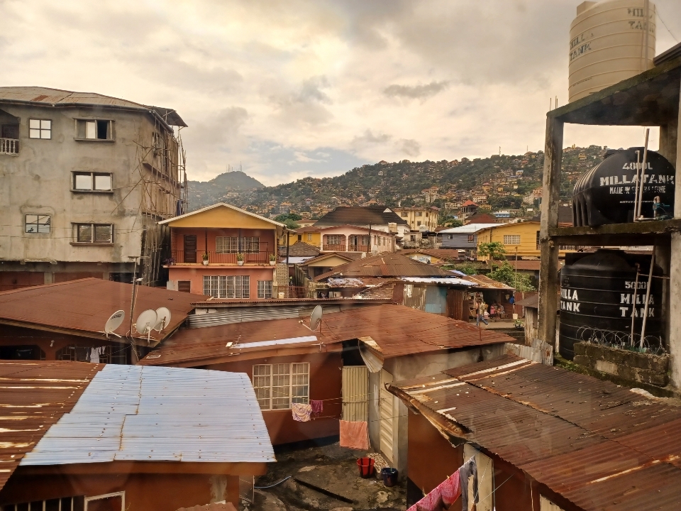Photo of aluminum and wood tops of dwellings. Hillside in background.