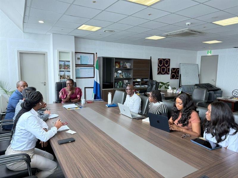 A photo of eight people around a table, including the Mayor of Freetown.