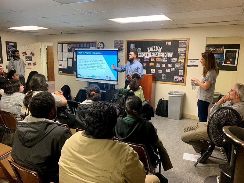 A group of people in a room looking at a presentation by the Transit and Intercity Capital Rail Program.